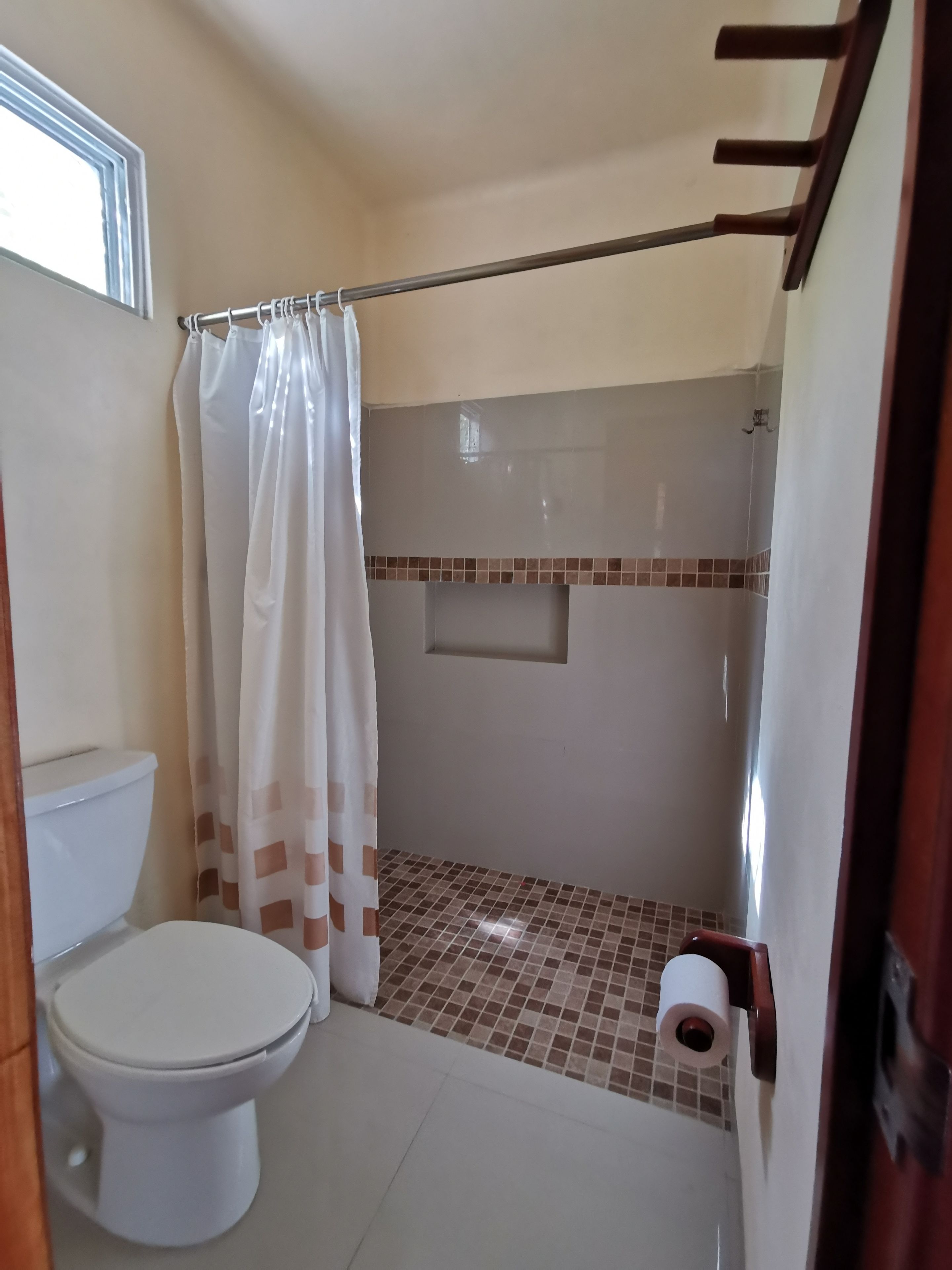 Ein Badezimmer mit Toilette, Dusche und einem kleinen Fenster.