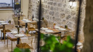 A restaurant with stone walls, wooden tables, and metal chairs. - Heritage Hotel Dea Hvar (Hvar)