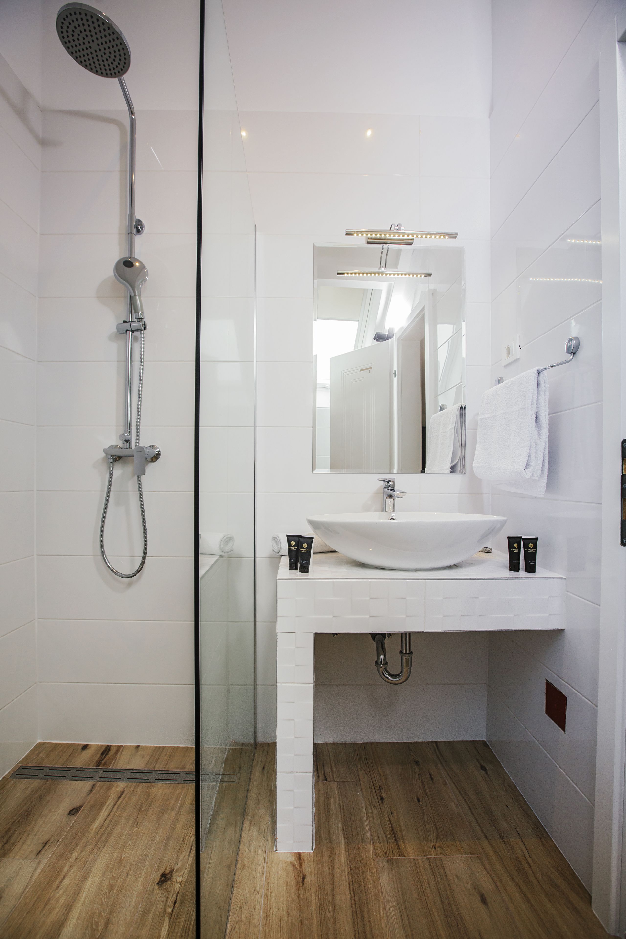 Une salle de bain moderne avec une douche à parois de verre, un lavabo blanc et un miroir au-dessus.