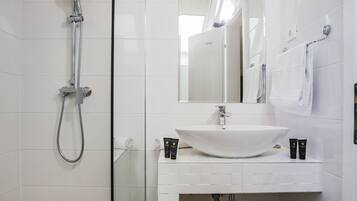 Une salle de bain moderne avec une douche à parois de verre, un lavabo blanc et un miroir au-dessus.