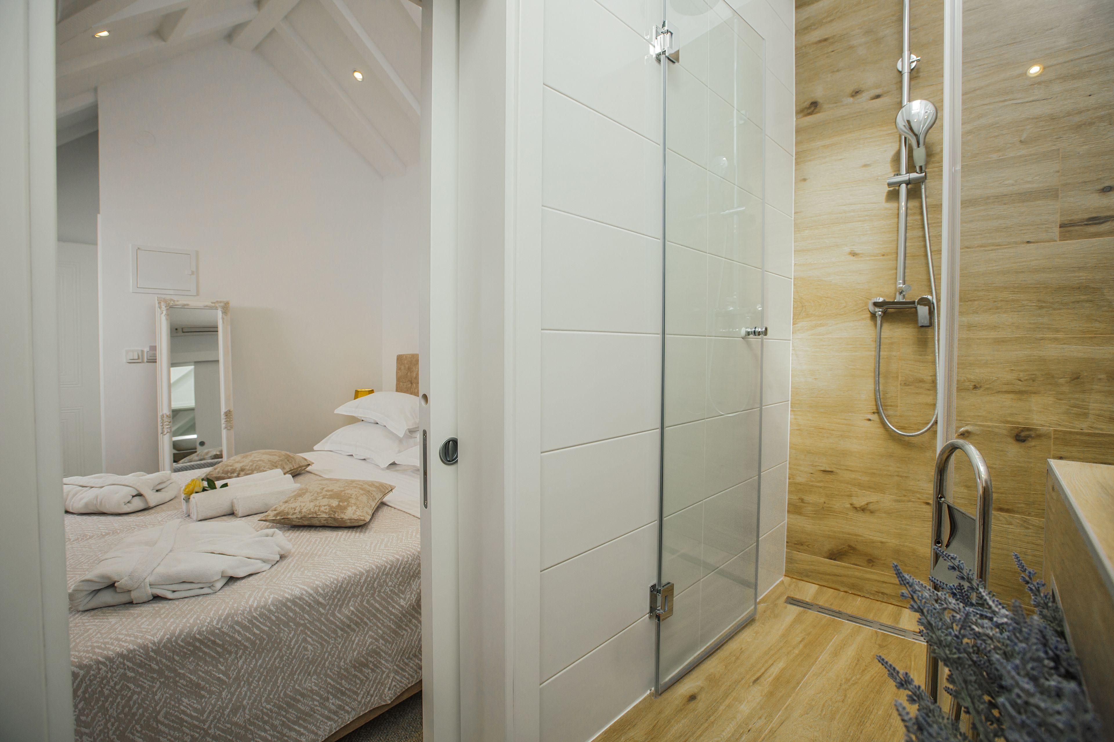 A modern bathroom with a glass shower enclosure, wooden wall paneling, and a visible sink area.