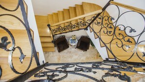 A wooden staircase with ornate black metal railings and a white wall in the background. - Heritage Hotel Dea Hvar (Hvar)