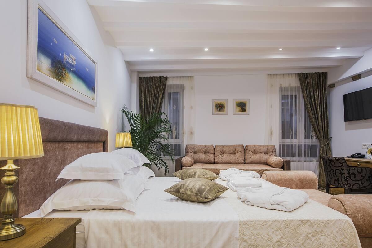 A hotel room with a bed, a sofa, a TV, and a lamp.