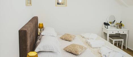 A bedroom with a bed, bedside table, lamp, and a desk with a mirror.