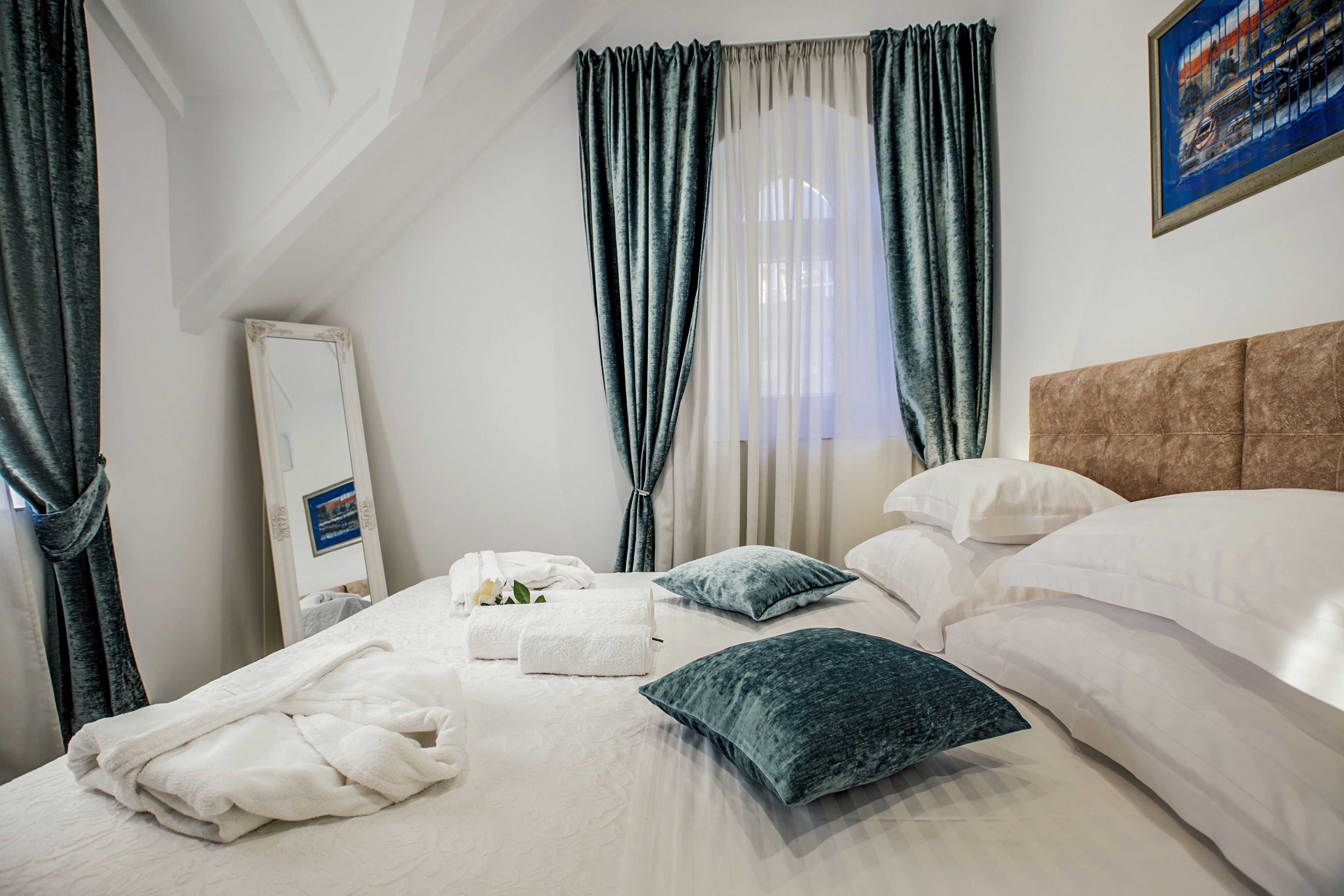 Una cama bien hecha con sábanas blancas, una almohada azul y una toalla blanca.