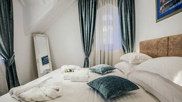 Una cama bien hecha con sábanas blancas, una almohada azul y una toalla blanca.