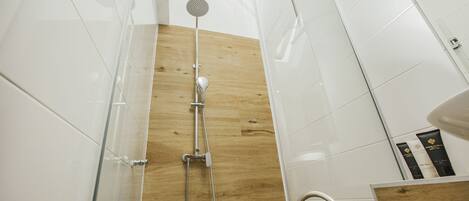 A modern bathroom with a shower, wooden panel wall, and white tiles.