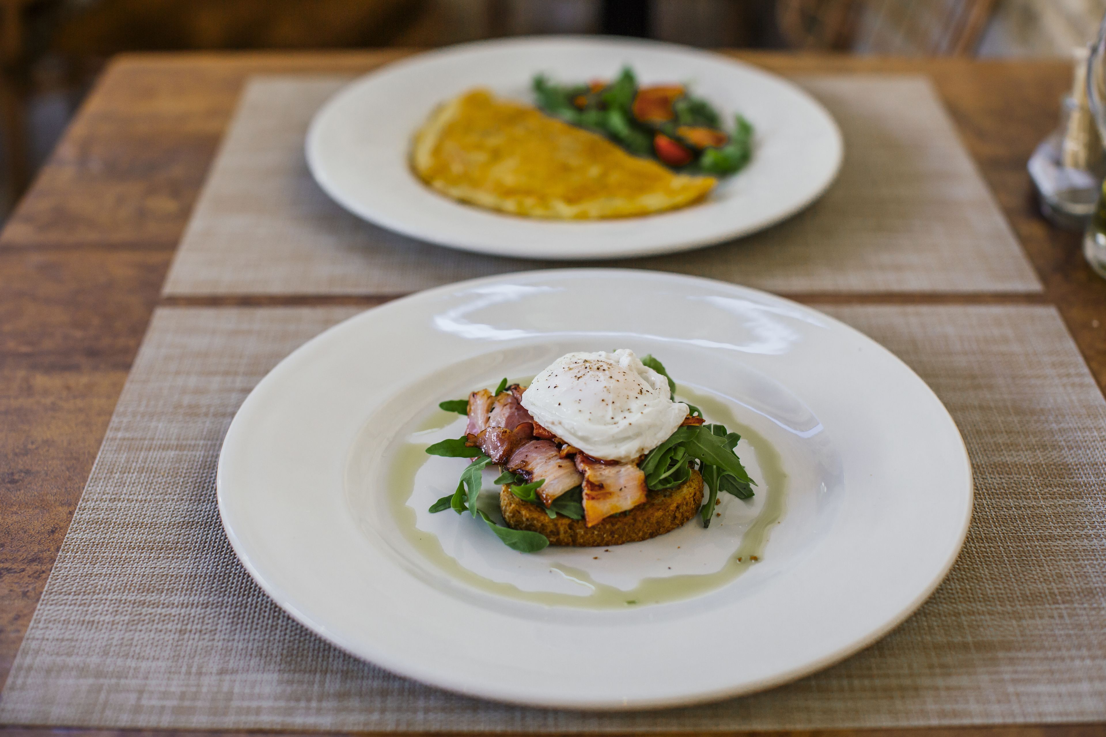 Two plates of food on a wooden table with a placemat.