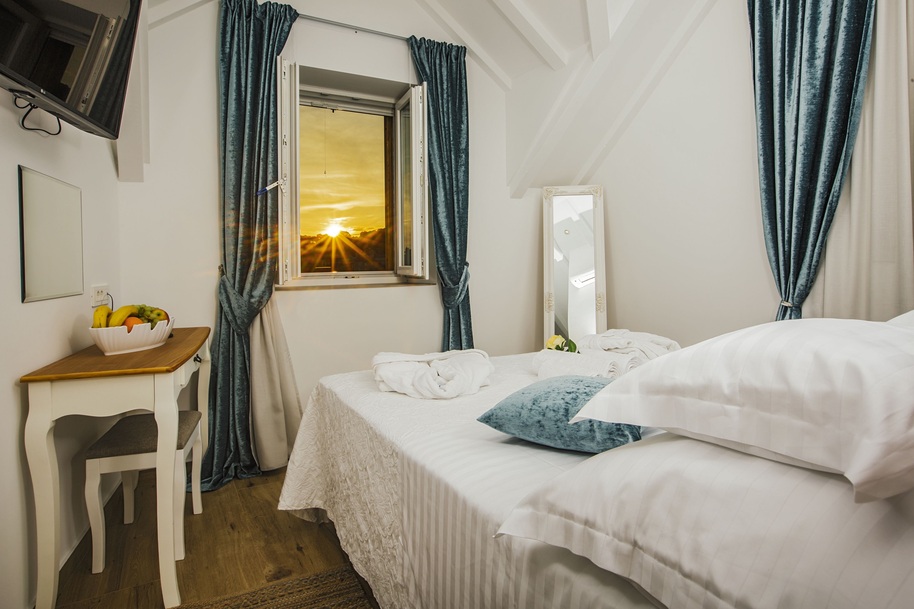 Une chambre à coucher avec un lit, un bureau, une chaise, une fenêtre avec des rideaux et un miroir.