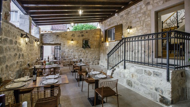 A restaurant with stone walls, wooden tables, and metal railings. - Heritage Hotel Dea Hvar (Hvar)