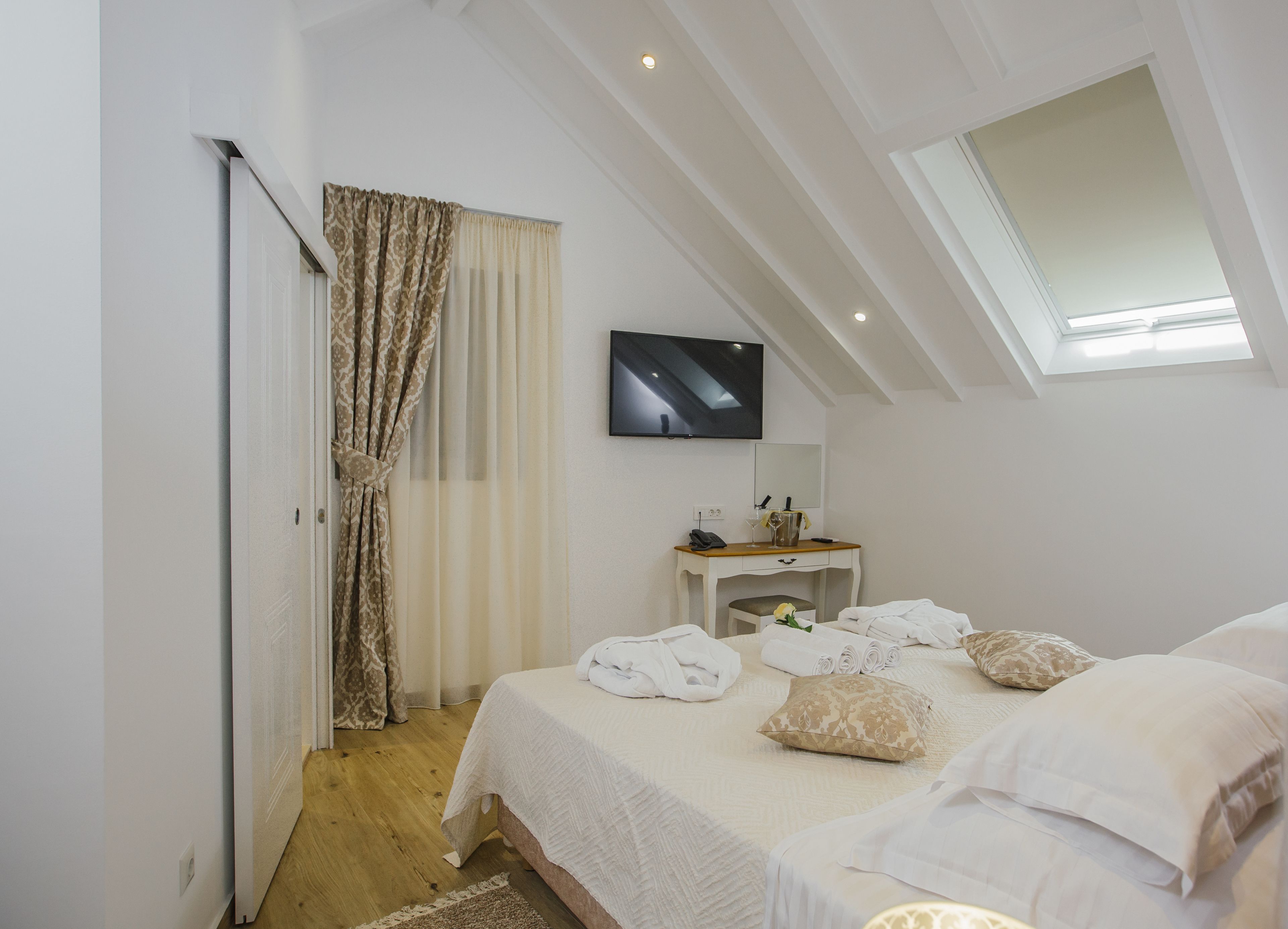Un dormitorio con cama, escritorio, televisor y tragaluz.