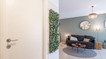 A modern living room with a grey sofa, a round coffee table, and a decorative plant wall.