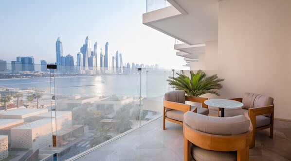 A modern balcony with a glass railing, offering a view of a city skyline and a body of water. - Luxury Sea View Apt in FIVE Resort on The Palm (Dubai)
