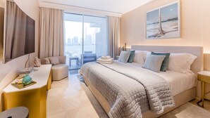 Et moderne hotelværelse med en stor seng, et skrivebord, en stol og udsigt over byen gennem vinduet.