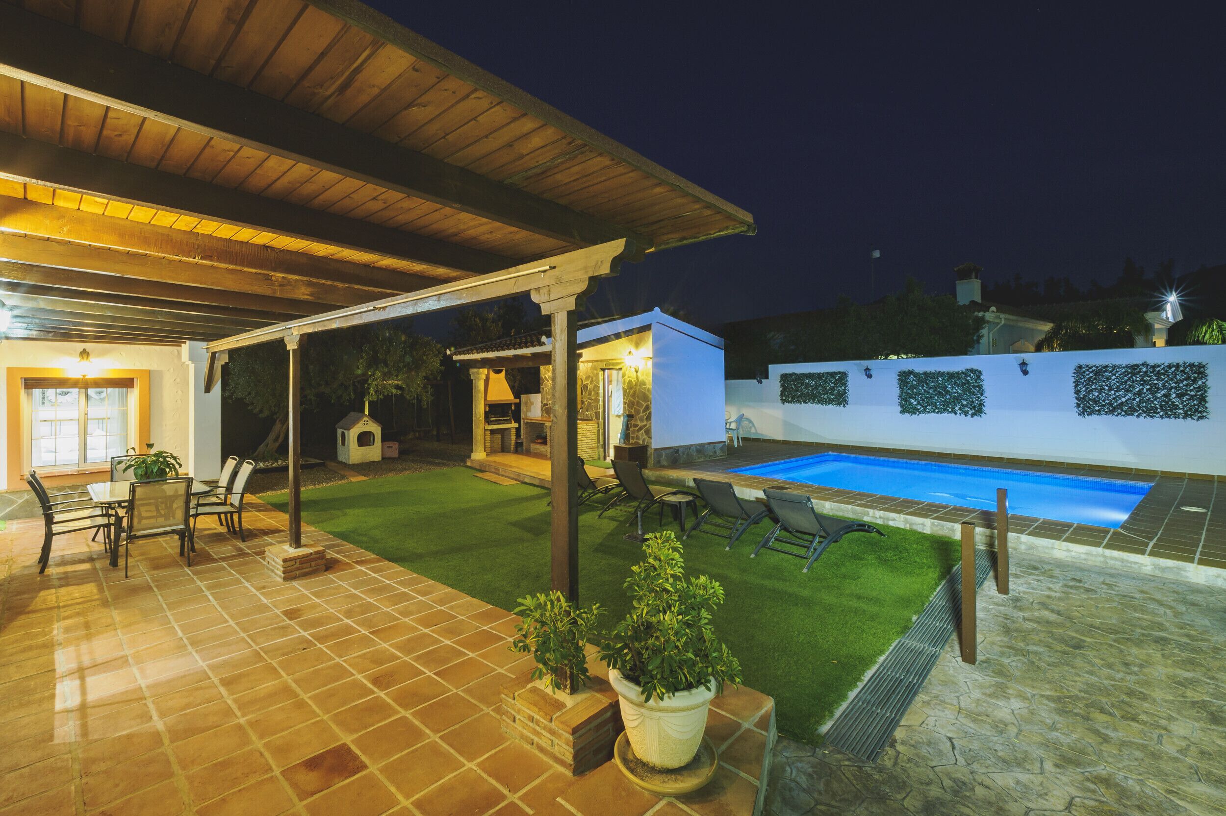 Un patio couvert avec une piscine, des meubles d’extérieur et une pelouse bien entretenue.