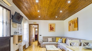 A cozy living room with a wooden ceiling, a sofa set, a coffee table, and a TV mounted on the wall. - Cubo's Casa La Dehesilla High Privacy and Pool  / Private pool / free wifi (Alhaurín el Grande)