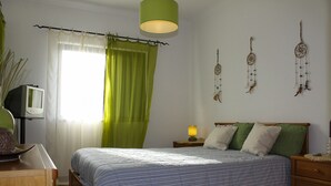 A bedroom with a bed, a nightstand, a lamp, a television, and wall decorations. - Condomínio Vilita, T1-Lt-5,F Pêra-Silves (Pêra)