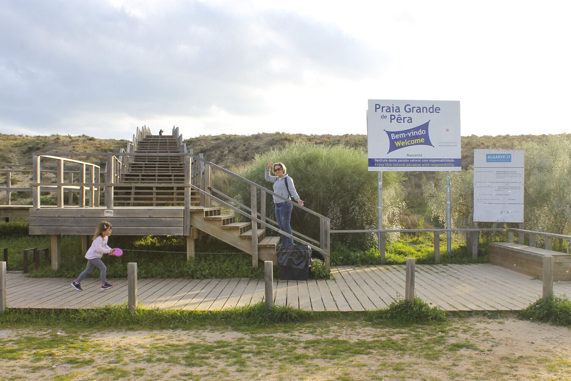 Una escalera de madera que conduce a una plataforma de observación con un letrero que dice 'Praia Grande de Pêra' y 'Bienvenido Welcome'.
