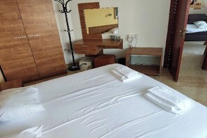 A hotel room with a large bed, a wooden wardrobe, a mirror, a small table, and a nightstand. - Charis Cozy Family Apart. at Sun Village  - ONLY 10 mins Walk to the Beach (Bourgas)