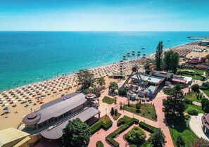 An aerial view of a beach resort with a large sandy beach, a Ferris wheel, and a central building with a curved roof. - Charis Cozy Family Apart. at Sun Village  - ONLY 10 mins Walk to the Beach (Bourgas)