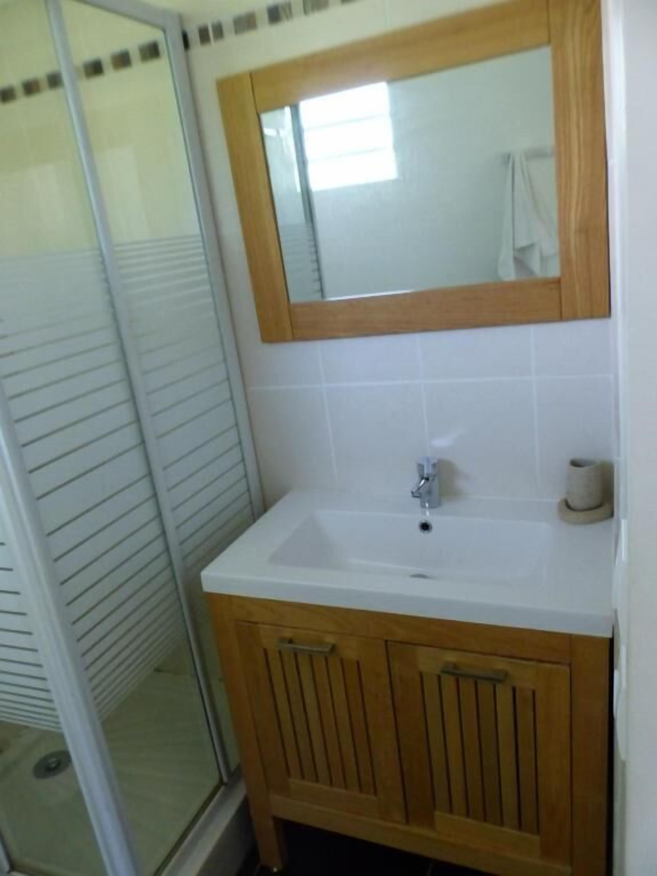 A bathroom with a white sink, wooden vanity, and a mirror.