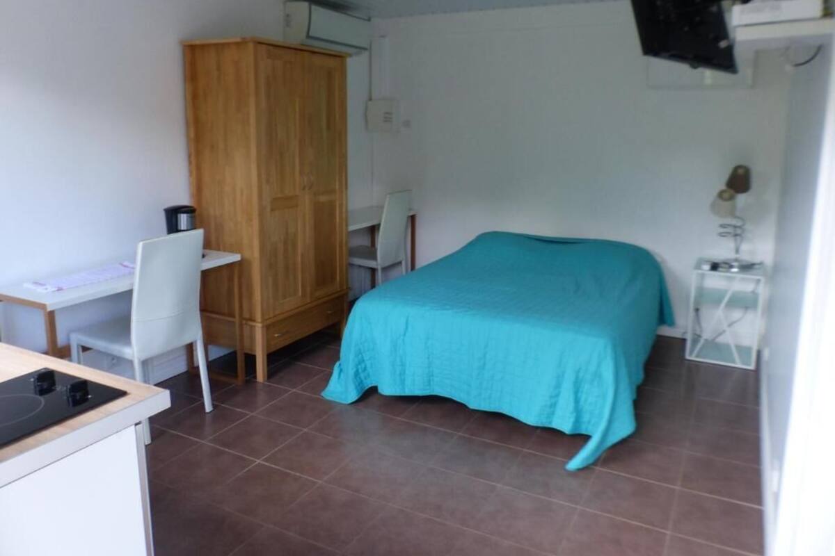 Une chambre à coucher comprenant un lit, un bureau, une chaise, une armoire et une petite table avec une lampe.