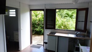 Une cuisine compacte avec une fenêtre donnant sur un jardin, un évier encastré et un petit réfrigérateur.