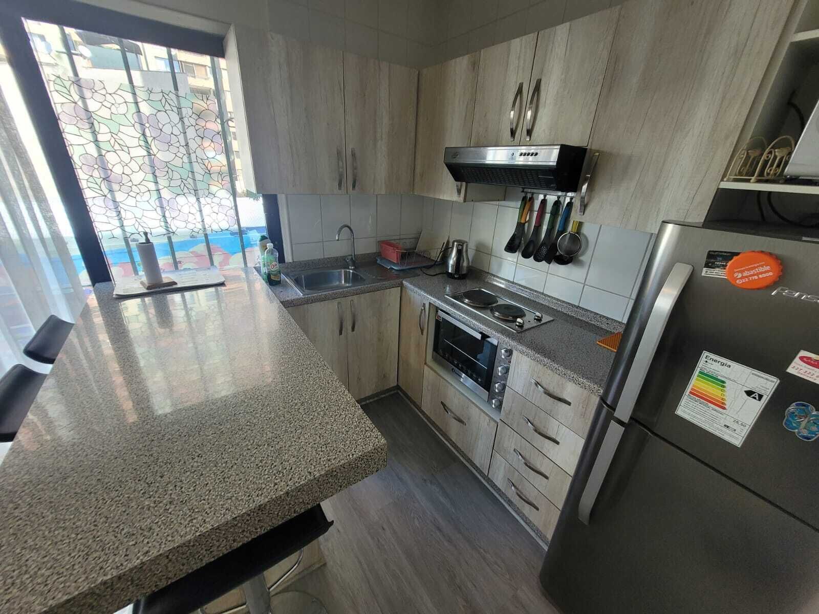 Una cocina moderna con encimeras de granito, electrodomésticos de acero inoxidable y un amplio ventanal con vistas.