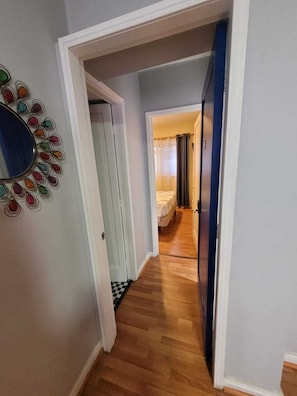 A hallway with a wooden floor, a blue door, and a bed in the background. - Casa Marcoleta (Santiago)