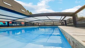 Une piscine dotée d’une zone abritée et offrant une vue sur un bâtiment en arrière-plan.