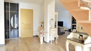 Un vaste espace de vie agrémenté d’un escalier en bois, d’un téléviseur et d’un vase décoratif contenant des fleurs.