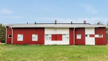 Un bâtiment rouge et blanc, surmonté d’un toit en métal, situé dans un espace verdoyant.