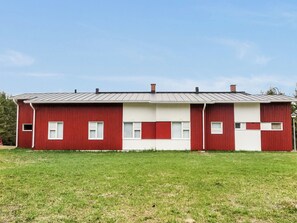 Un bâtiment rouge et blanc, surmonté d’un toit en métal, situé dans un espace verdoyant.