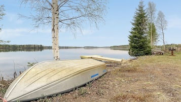 Un cadre idyllique au bord du lac, avec un bateau, un arbre et un banc.