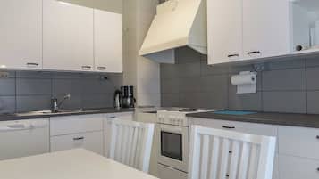 Une cuisine moderne avec des meubles blancs, une cuisinière et une machine à café.