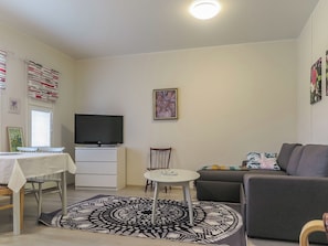 A living room with a flat-screen TV, a dining table, a sofa, and a patterned rug. - Itäkoski 2 by Interhome (Keminmaa)