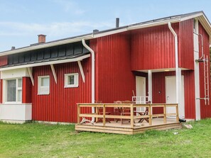 Un edificio rosso con un portico e un patio in legno.
