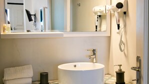A bathroom with a white sink, a mirror, a hairdryer, and a towel.