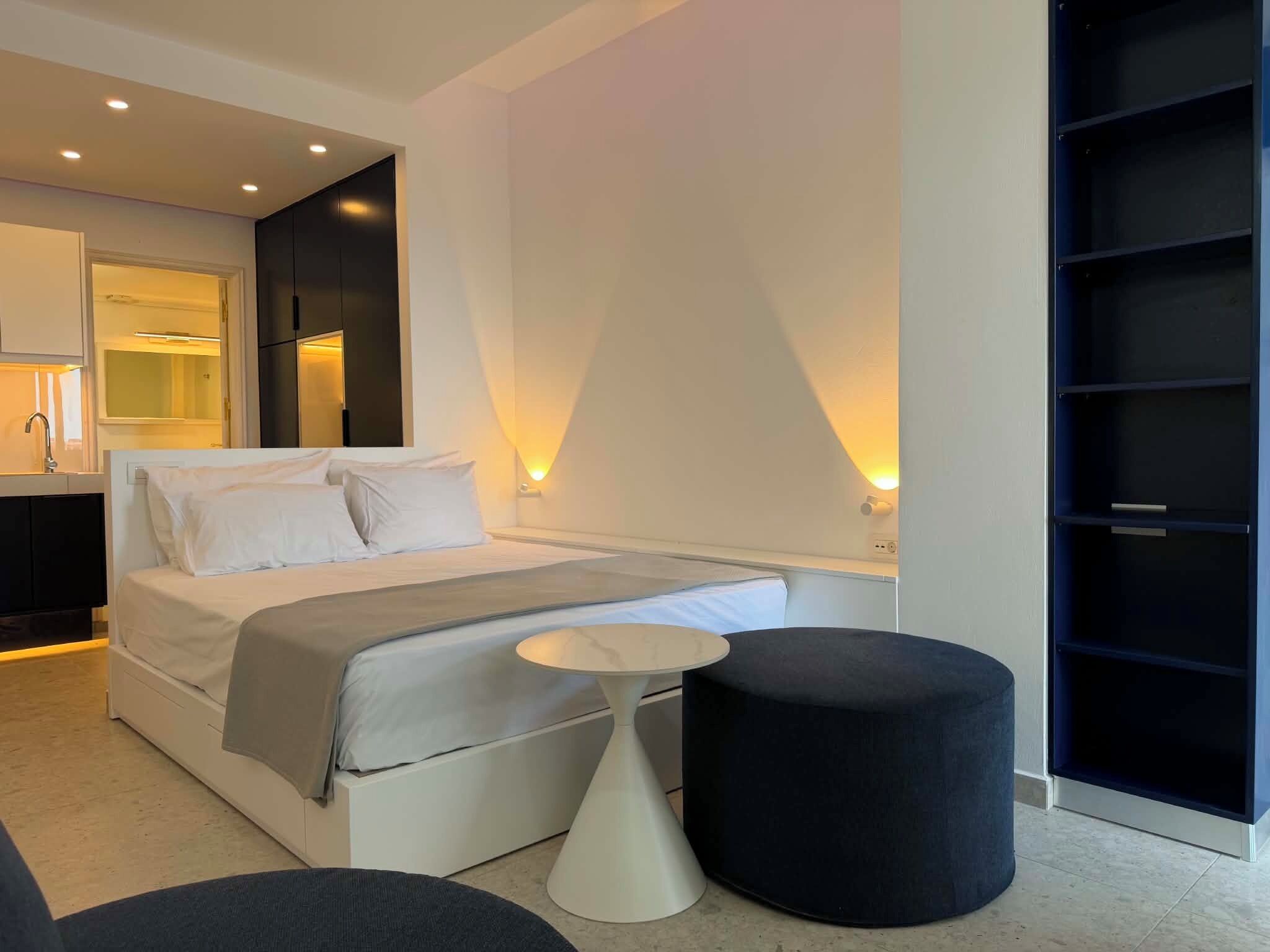 A modern bedroom with a bed, bedside tables, and a wardrobe.