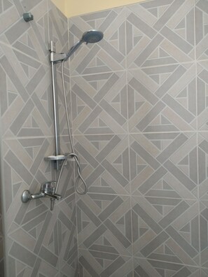 Um chuveiro com um padrão geométrico de azulejos na parede.
