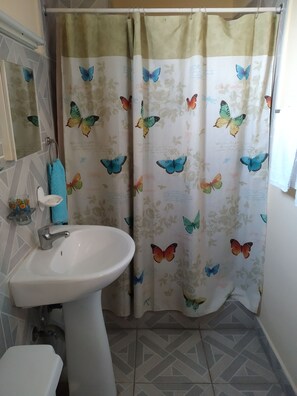 A bathroom with a white sink, a blue towel, and a shower curtain with butterfly patterns. - Casa Nidia Hab Indep (Havana)