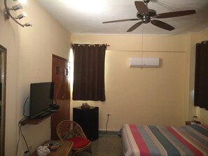 A bedroom with a bed, a television, a ceiling fan, a small table with a chair, and an air conditioning unit. - Casa Nidia Hab Indep (Havana)