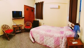 A hotel room with a bed, a desk with a computer, a chair, a television, and an air conditioning unit. - Casa Nidia Hab Indep (Havana)