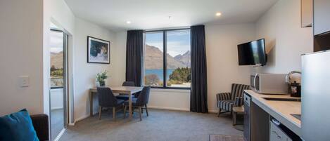 Una habitación de hotel moderna con comedor, sofá, televisor y zona de cocina.