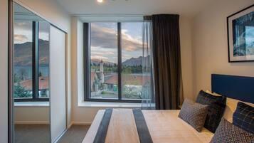 A hotel room with a large bed, a view of mountains and a lake, and a modern design.