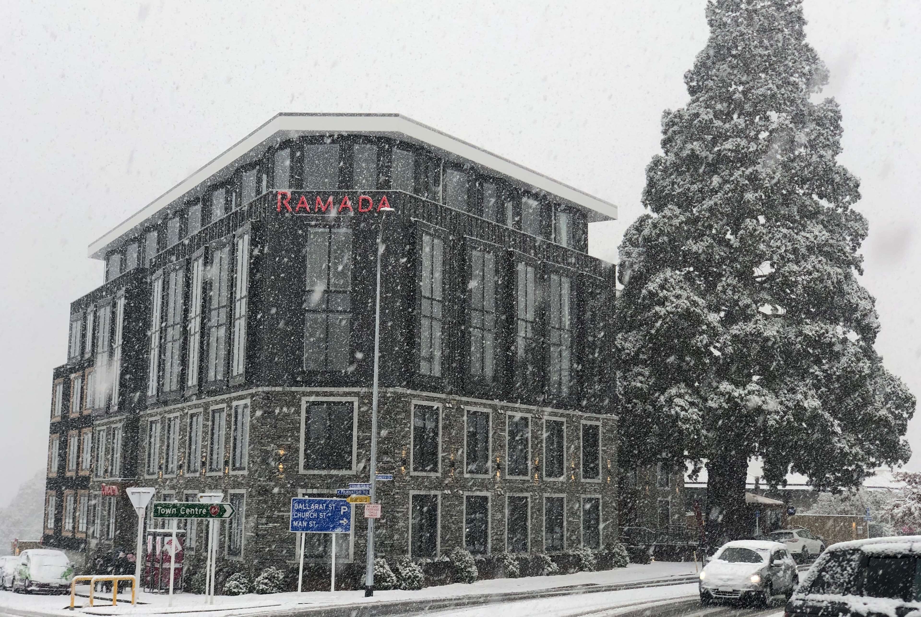 Un bâtiment portant l’inscription « RAMADA », avec une enseigne indiquant « Centre-ville » et « Ballarat P », par une journée de neige.