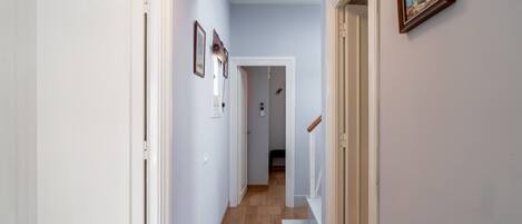 A hallway with white doors, a wooden staircase, and a framed picture on the wall.