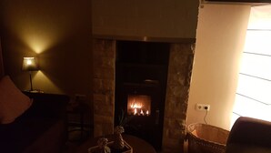 Una sala de estar acogedora con chimenea, una lámpara y una cesta.
