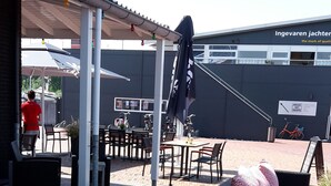 Un espacio al aire libre con mobiliario de mimbre, un porche cubierto y un cartel que indica una vivienda de calidad.