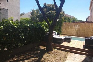 Ein Garten mit einer Holzterrasse, einem kleinen Pool und einem Baum.